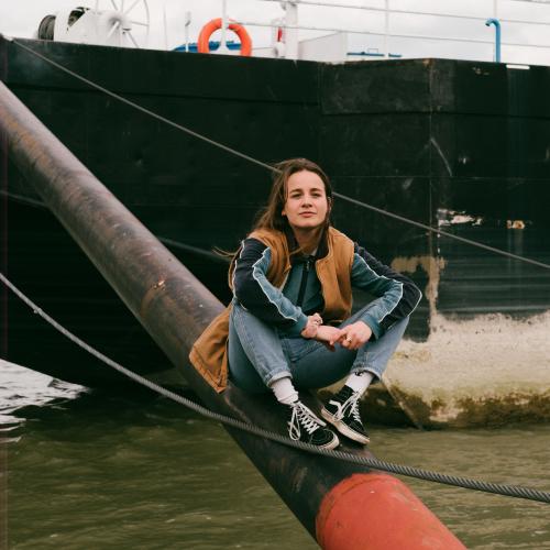 Tereza sitzt vor einem Schiff auf der Donau